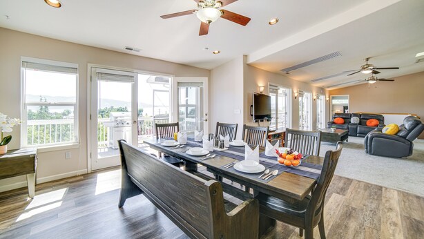 A spacious dining area with a wooden table set for four, surrounded by chairs, and a ceiling fan overhead.
