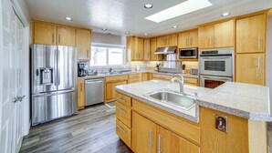 A modern kitchen with wooden cabinets, stainless steel appliances, and a granite countertop.