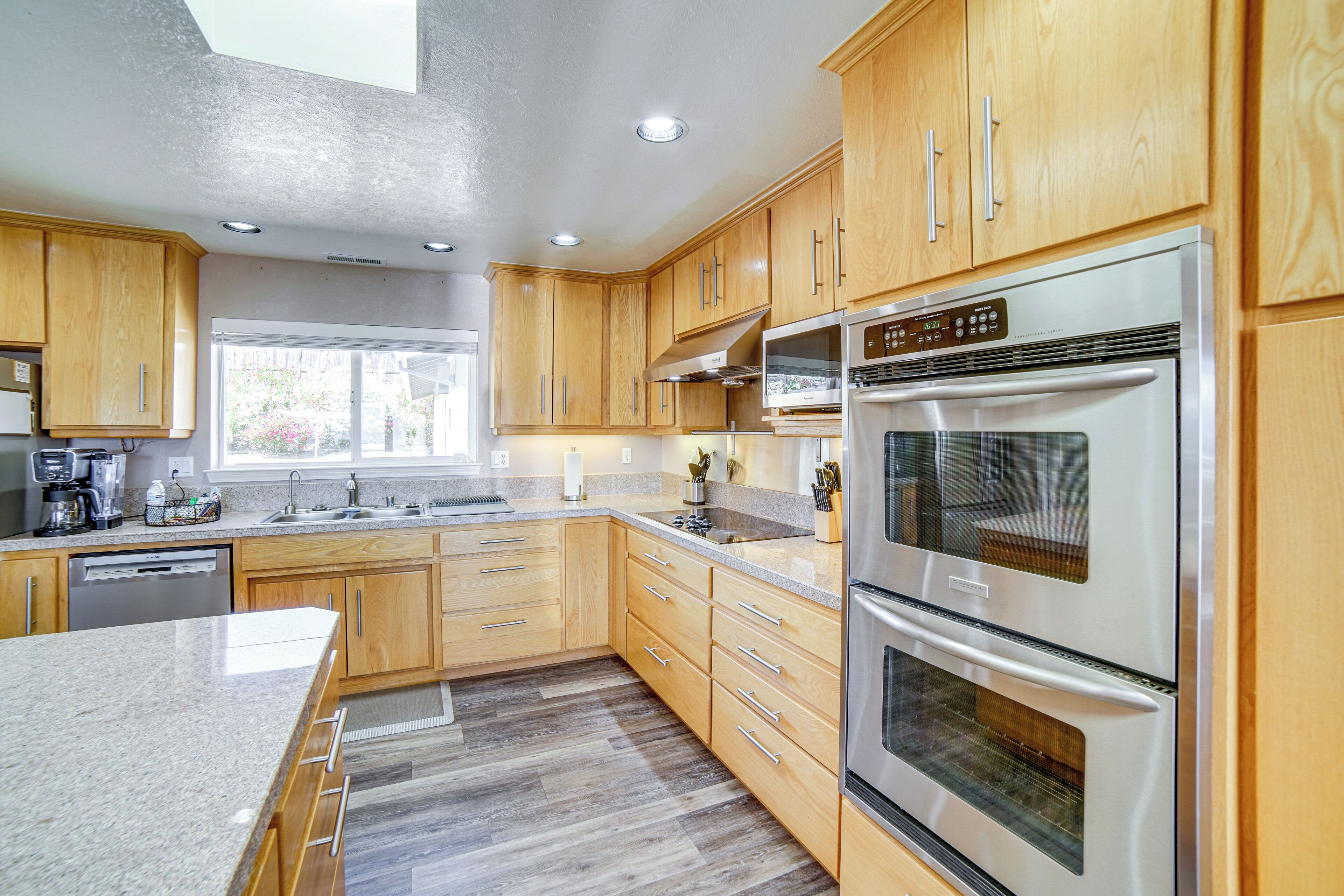 Una cucina moderna con mobili in legno, elettrodomestici in acciaio inossidabile e un'ampia finestra che garantisce luce naturale.