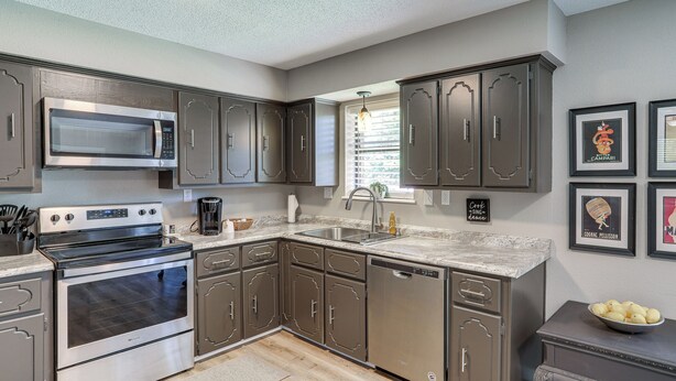 A modern kitchen with stainless steel appliances, dark cabinetry, and a granite countertop. - Rural Melbourne House With Deck! (Melbourne)