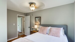 A bedroom with a bed, a nightstand, a lamp, a framed picture, and a door leading to another room. - Rural Melbourne House With Deck! (Melbourne)