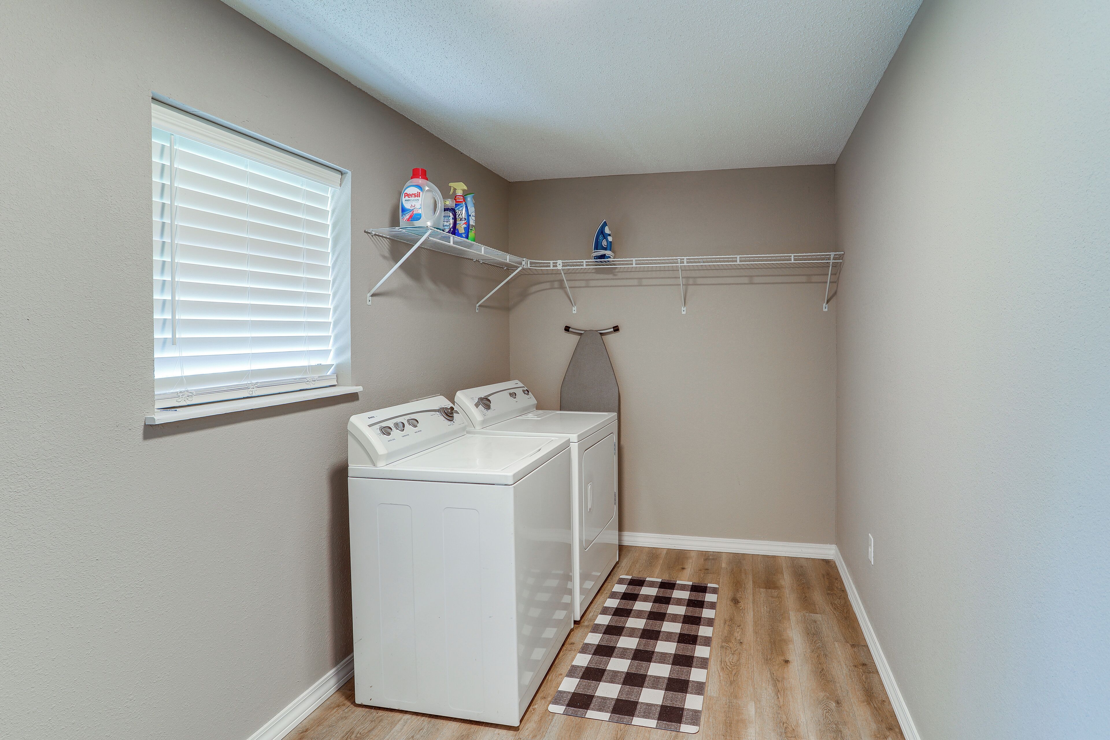 A laundry room with a washing machine, dryer, and shelves above the machines.