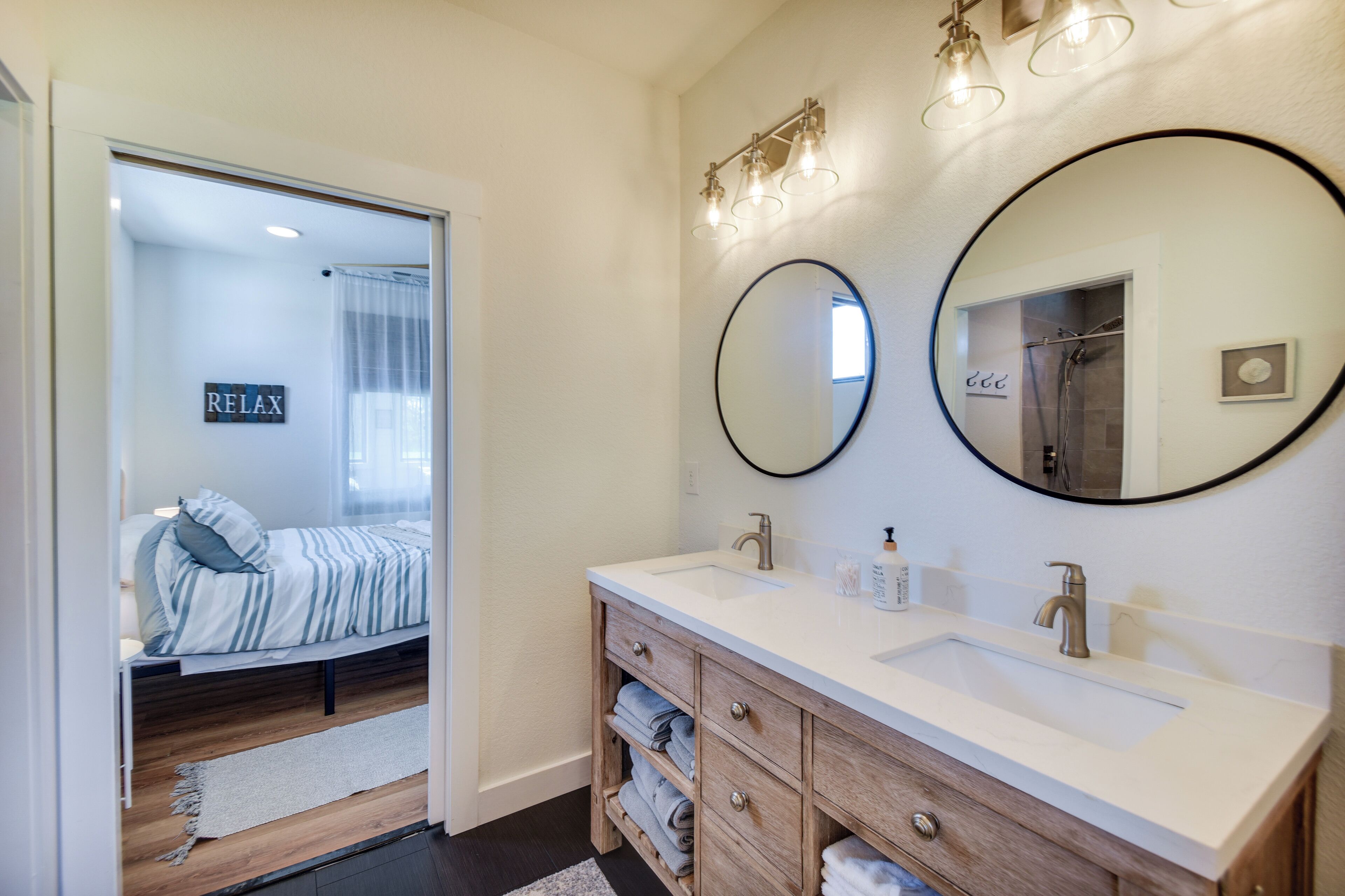 A modern bathroom with a double sink, wooden vanity, and a large mirror.