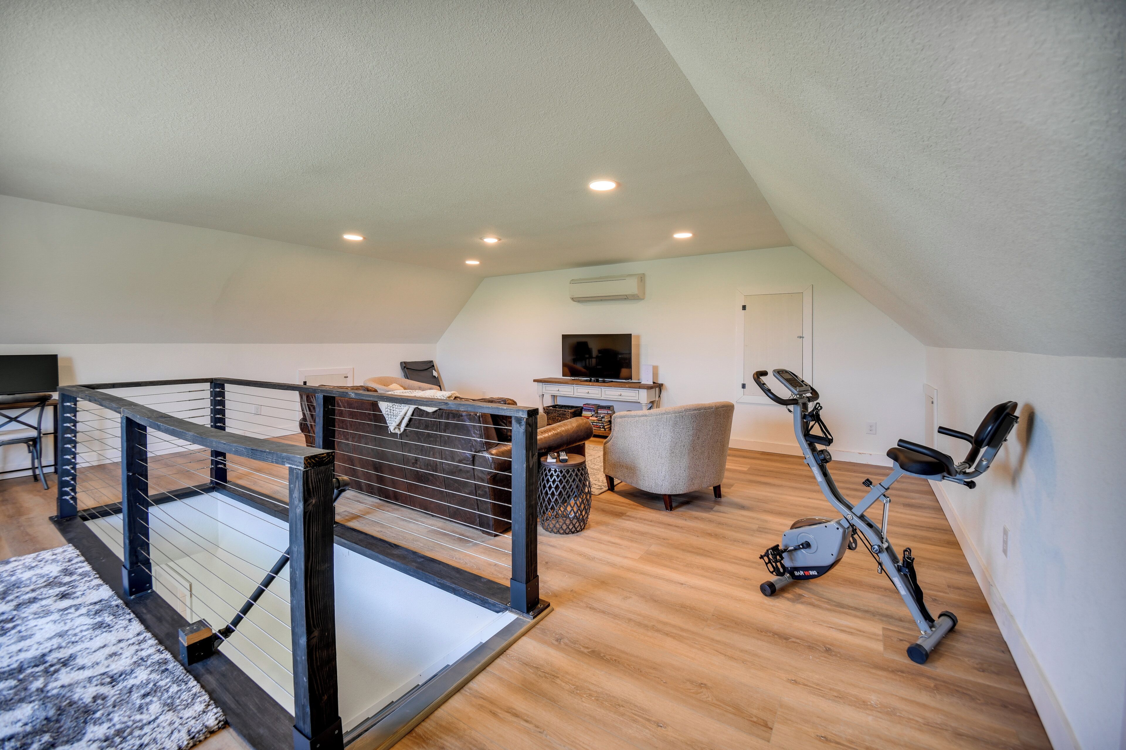 Quarto no sótão com cama beliche, bicicleta de exercícios e uma televisão no canto.