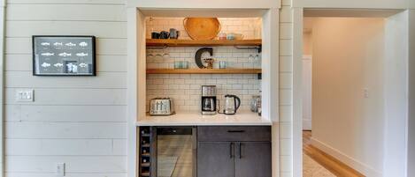 Cocina compacta con muebles blancos, horno empotrado y cafetera sobre la encimera.