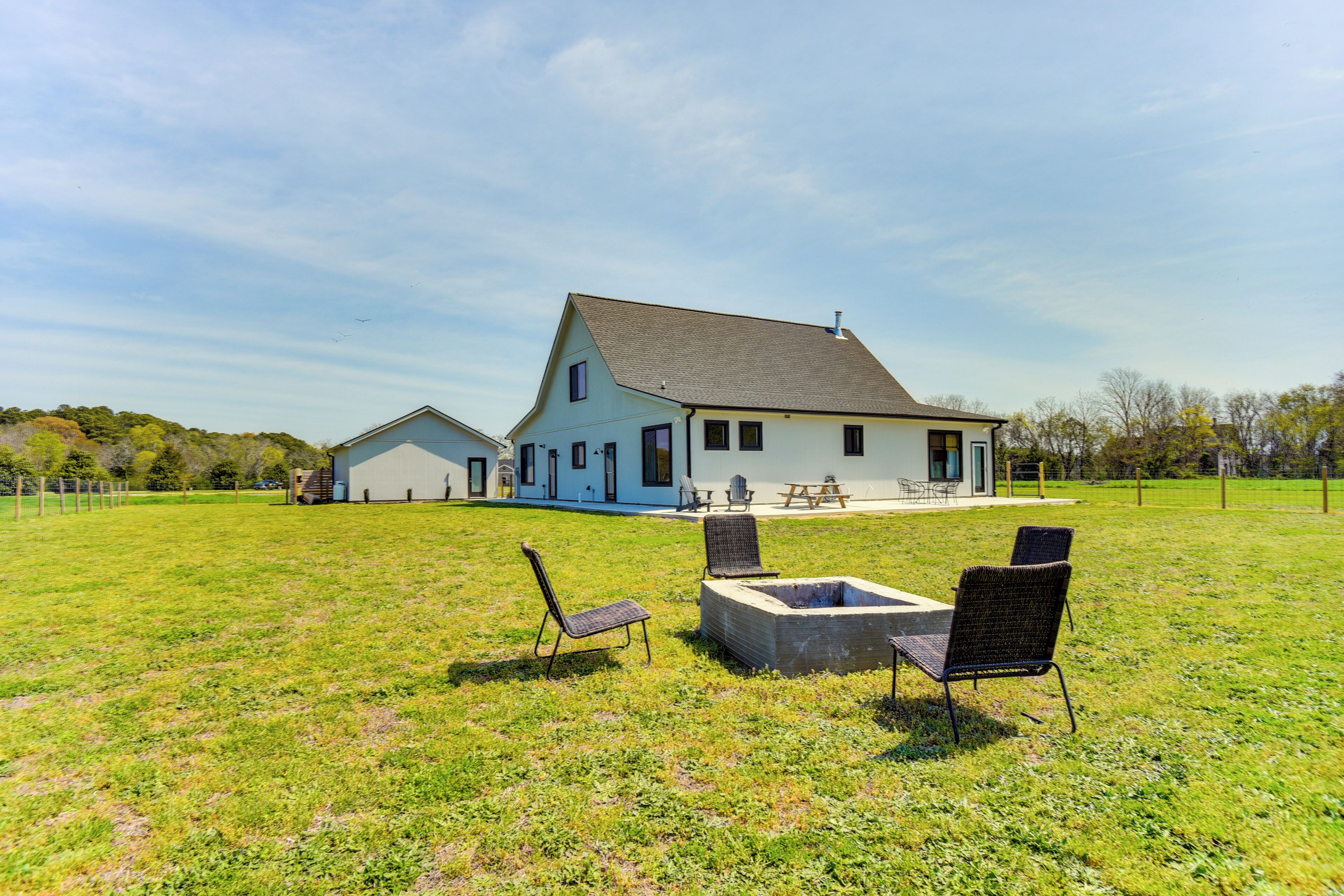 A large house with a spacious lawn, outdoor seating, and a fire pit.