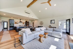A spacious living area with a large L-shaped sectional sofa, a dining table, and a kitchen in the background. - Stunning Chesapeake Bay Farmhouse w/ Dock & Kayaks (Machipongo)