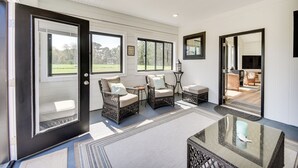 A spacious room with large windows, wicker furniture, and a glass table. - Stunning Chesapeake Bay Farmhouse w/ Dock & Kayaks (Machipongo)