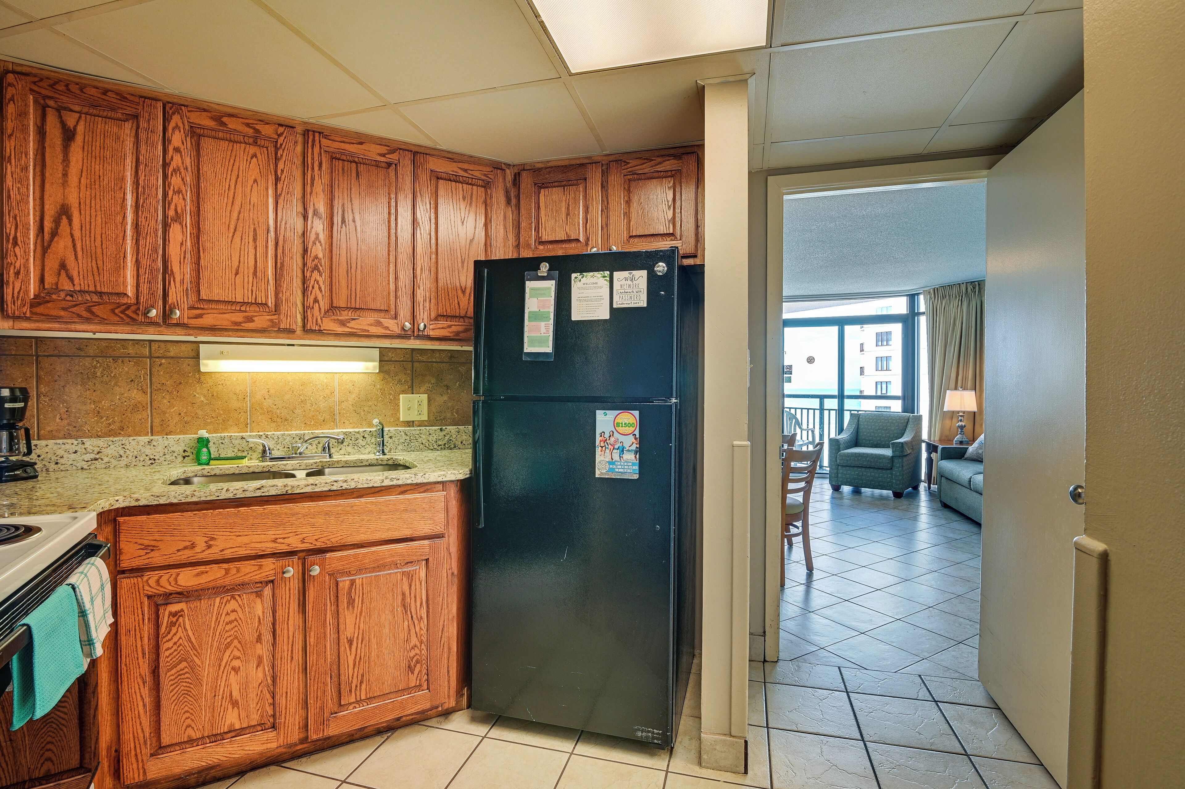 A kitchen with wooden cabinets, a black refrigerator, and a tiled backsplash.