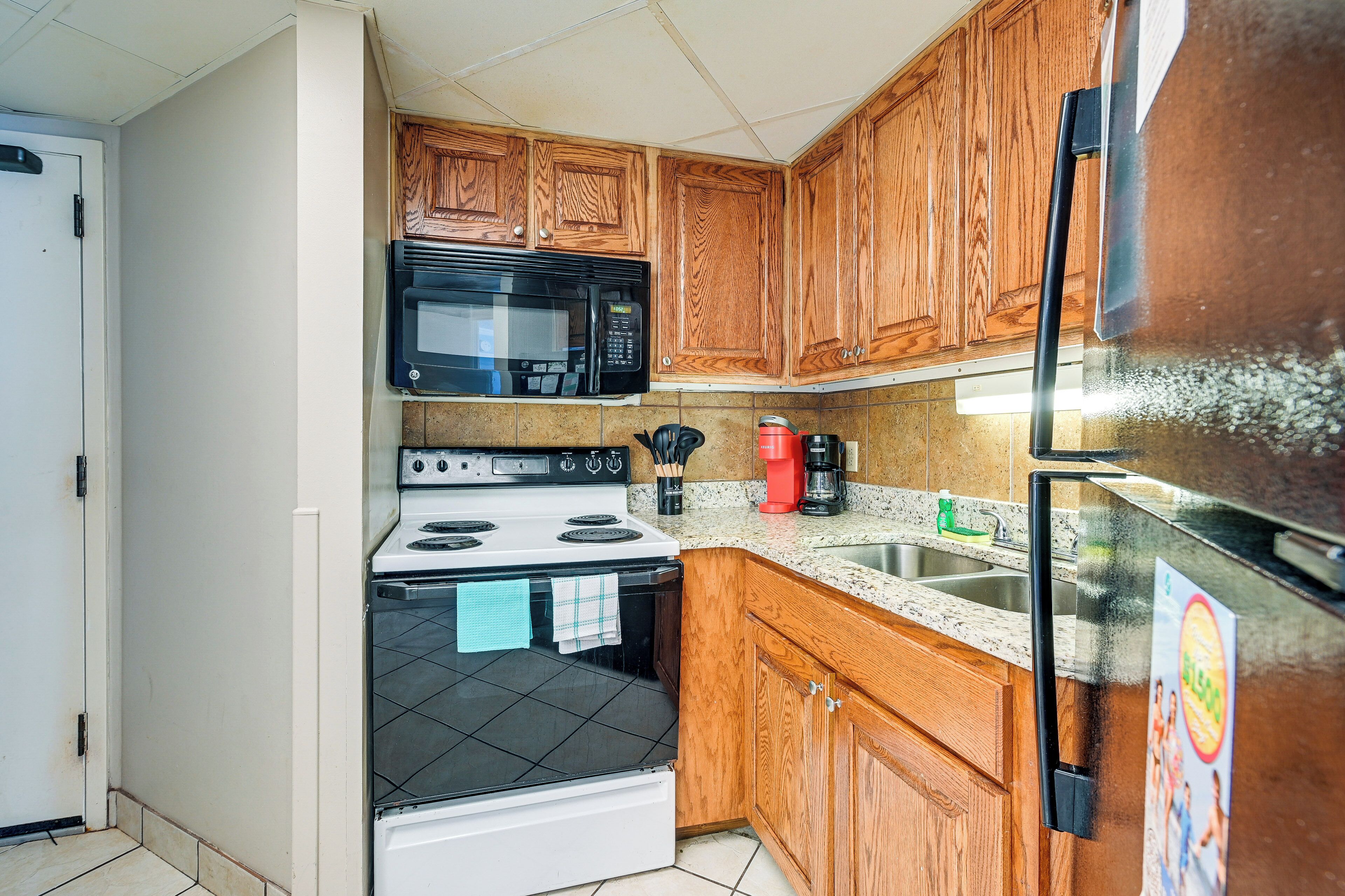 A kitchen with wooden cabinets, a microwave, stove, refrigerator, and a coffee maker.