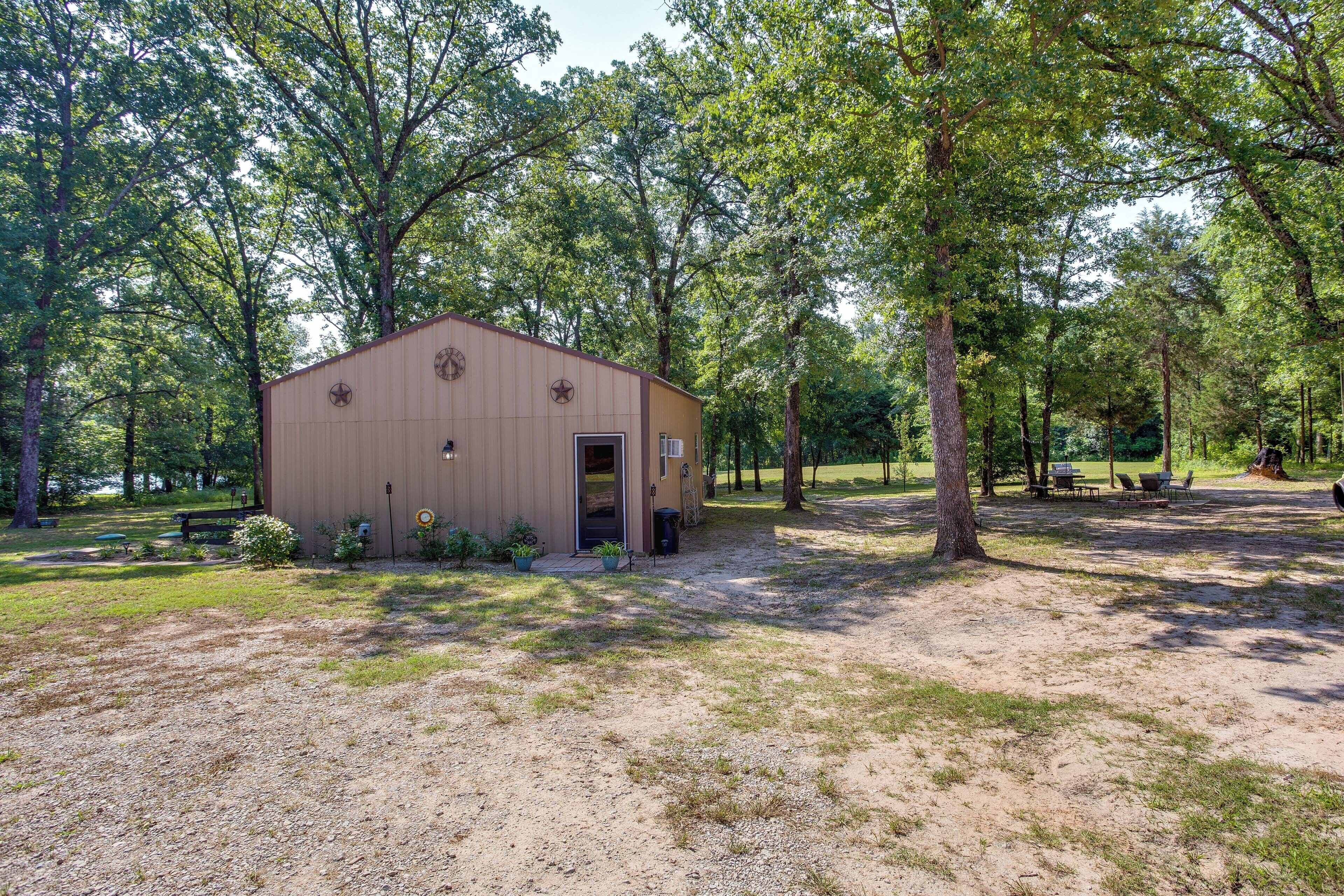 A small, single-story building with a door and windows, surrounded by trees and grass.