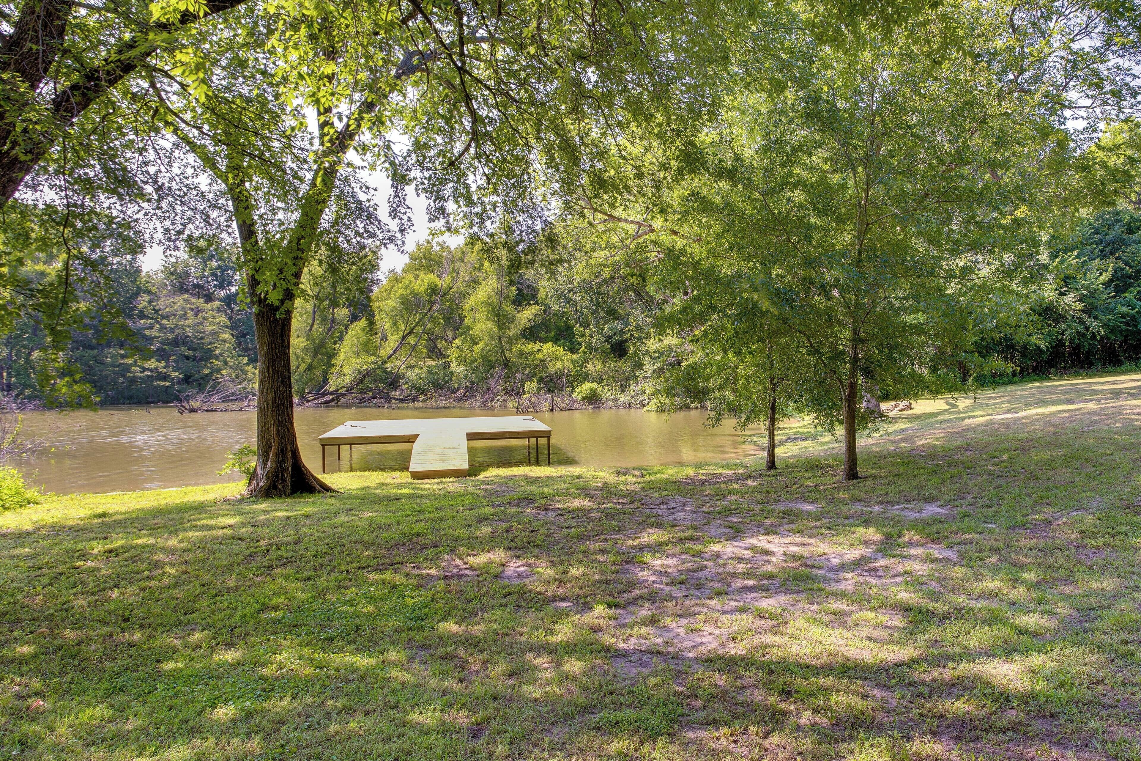 A lakeside park with a picnic table and a wooden deck by the water.