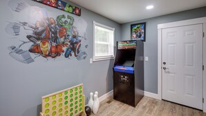 Una habitación con bolera, una puerta y una pared decorada con ilustraciones de superhéroes.