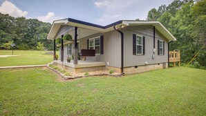 A modern two-story house with a covered porch, a wooden deck, and a well-maintained lawn.