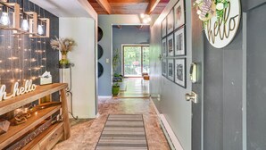 A hallway with a wooden bench, a 'hello' sign, string lights, and framed pictures on the walls. - 'alpine House' Modern Delevan Cabin on 2 Acres (Delevan)