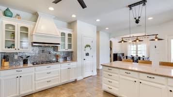A spacious kitchen with white cabinetry, a central island, and a ceiling fan.
