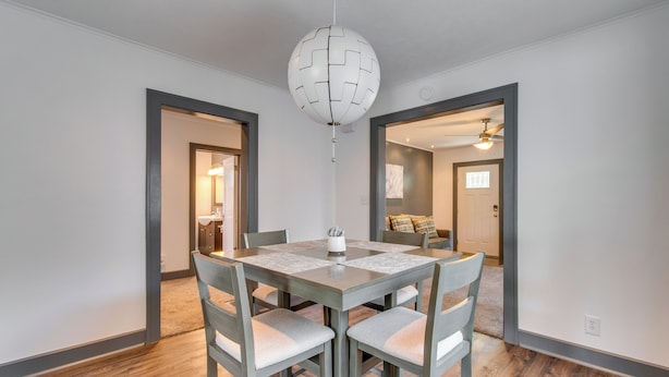 A dining area with a square table, four chairs, and a unique ceiling light.