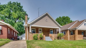 A two-story house with a front porch, brick exterior, and a chimney.