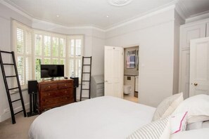 Cozy retreat with a large bed, dresser, and TV, featuring a loft area and a bathroom.
