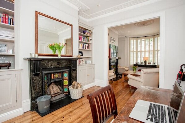 Cozy living room with a fireplace, large mirror, and bookshelf, perfect for relaxing and working.