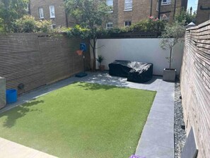 Enjoy the serene atmosphere of this backyard with a lush lawn, outdoor seating area, and a charming garden.