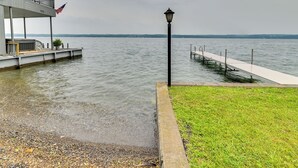 Une propriété située au bord de l’eau, dotée d’un quai s’étendant dans une zone d’eau calme, d’un lampadaire et d’une pelouse.