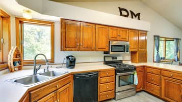 A kitchen with wooden cabinets, a stainless steel sink, a coffee maker, a microwave, and a stove.