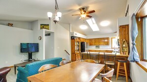 A spacious kitchen with wooden cabinets, a dining table, and a bar area. - Faribault Home w/ Deck Near Cedar Lake Boat Ramp! (Faribault)