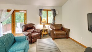 A living room with a brown leather sofa, a teal patterned sofa, a coffee table, and a lamp. - Faribault Home w/ Deck Near Cedar Lake Boat Ramp! (Faribault)