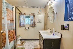 A bathroom with a shower curtain, toilet, sink, and mirror. - French Lick Getaway w/ Deck, Grill & Fire Pit! (French Lick)