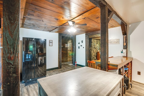A spacious room with a wooden ceiling, a large table, and a ceiling fan.