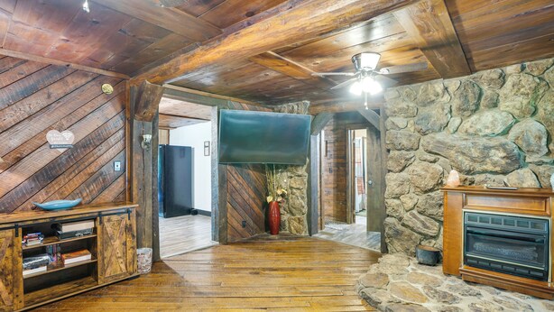 A rustic interior with wooden beams, a stone wall, a fireplace, and a television. - French Lick Getaway w/ Deck, Grill & Fire Pit! (French Lick)
