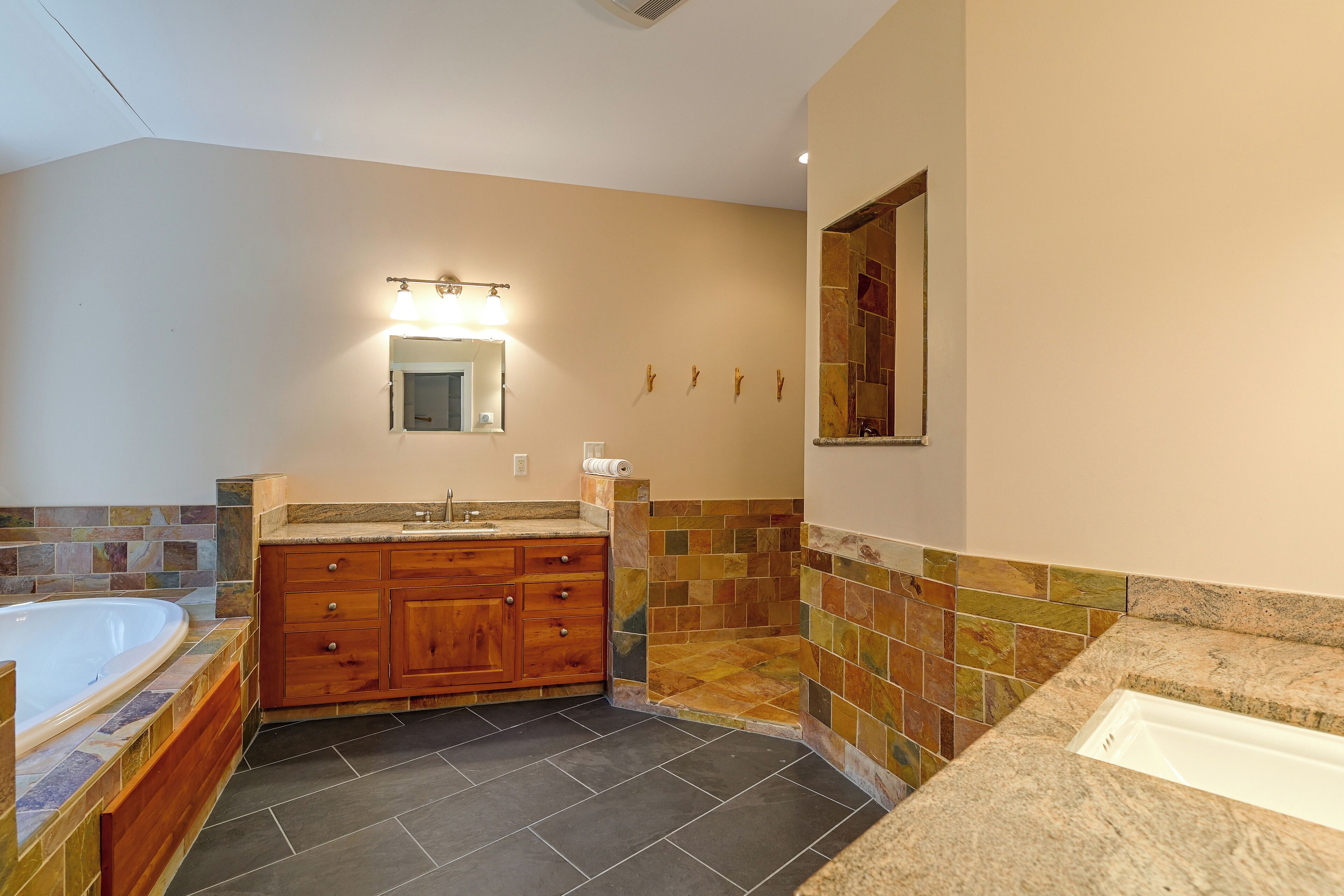 A bathroom with a wooden vanity, a bathtub, and a shower area.