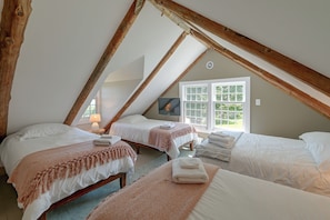 A cozy attic bedroom with two beds, a television, and a window with a view of greenery. - Marlboro Escape: 9 Mi to Mount Snow Resort! (Wilmington)