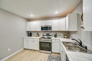 A modern kitchen with white cabinets, stainless steel appliances, and a marble countertop.
