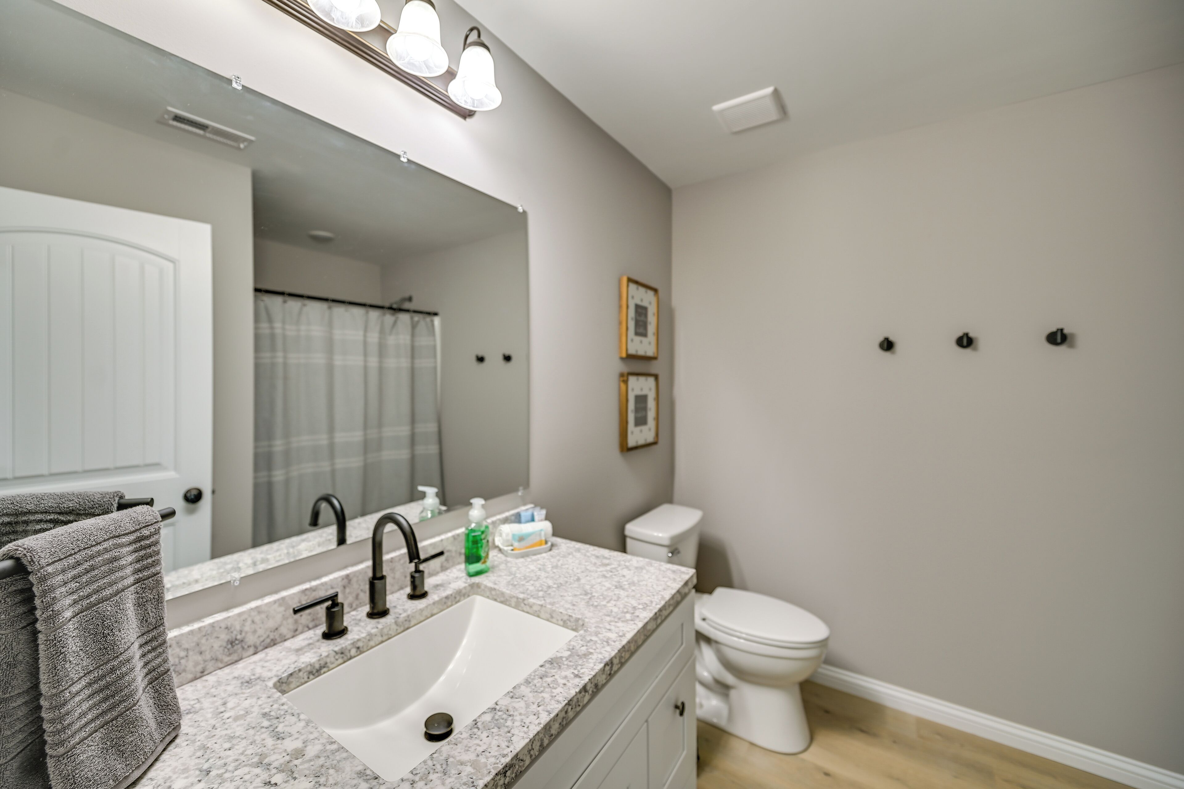 Une salle de bain avec un lavabo blanc, deux robinets, un miroir et des toilettes.