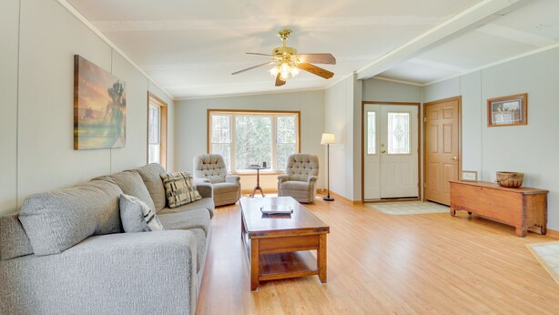 A spacious living room with a wooden floor, a ceiling fan, a sofa set, and a coffee table. - Near Waterville: Cozy Midcoast Vacation Rental! (Albion)