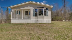 A single-story house with a covered porch, a small deck, and a clear blue sky in the background. - Near Waterville: Cozy Midcoast Vacation Rental! (Albion)
