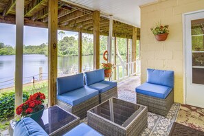 A covered outdoor seating area with wicker furniture and a view of a lake. - Mays Landing Rental on Great Egg Harbor River! (Mays Landing)