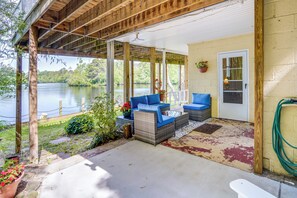 A covered patio with wicker furniture and a view of a lake.