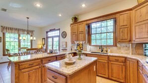 A spacious kitchen with wooden cabinets, a large island, and ample natural light from windows.