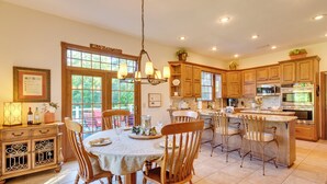 A spacious kitchen with wooden cabinets, a dining area with a table set for four, and a large island with seating.
