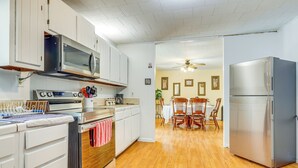 A kitchen with white cabinets, stainless steel appliances, and wooden flooring.