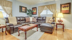 A living room with a brown leather sofa, a wooden coffee table, and a lamp on a side table.