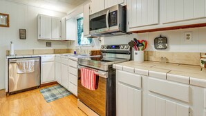 A kitchen with white cabinets, a stainless steel oven, a microwave, and a wooden countertop.