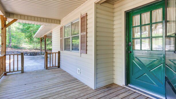 A covered porch with a green door and windows with shutters.