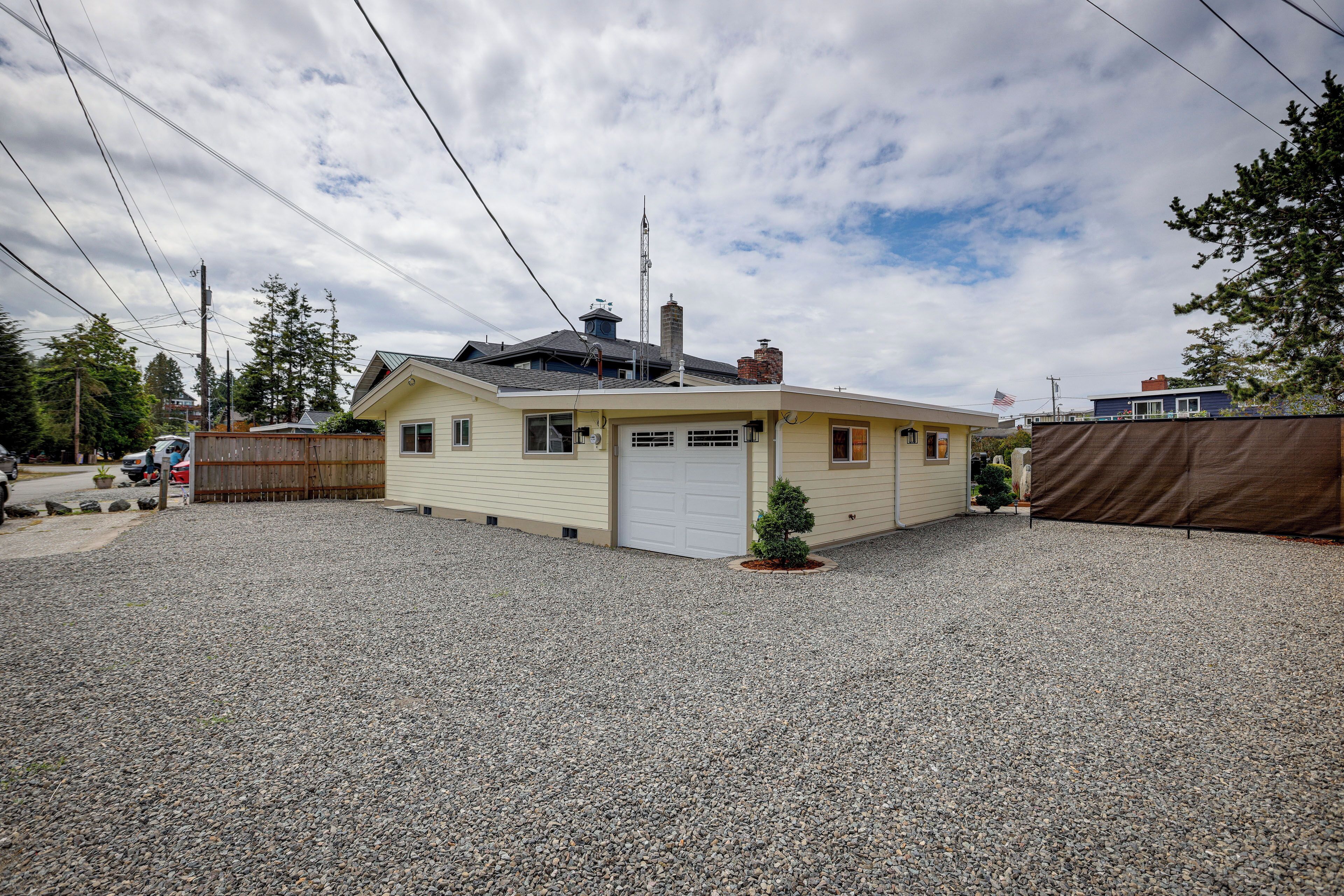 Une maison de plain-pied avec un garage, un petit jardin devant et une allée en gravier.
