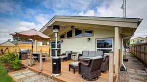 Une terrasse couverte, aménagée avec du mobilier d’extérieur, un barbecue et une pergola agrémentée d’une lampe.