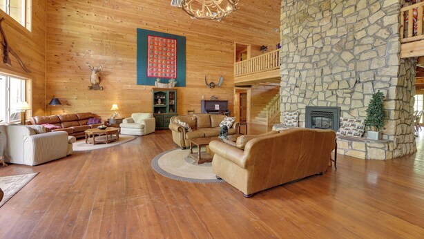 A spacious living area with wooden floors, a stone fireplace, and a cozy fireplace area.