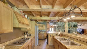 A spacious kitchen with wooden cabinets, a granite countertop, and a stone backsplash.